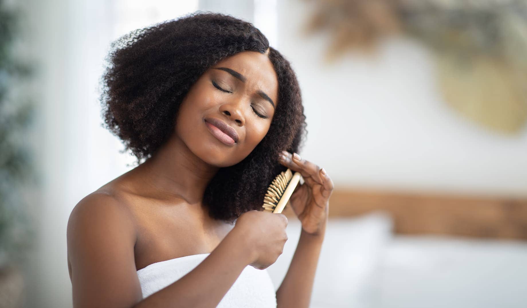 femme qui peigne ses cheveux crépus avec difficulté